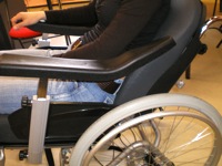 Fauteuil Inovys  en noir, centré sur le coté gauche, roues et accoudoir,  lors de l'essai à Hacavie